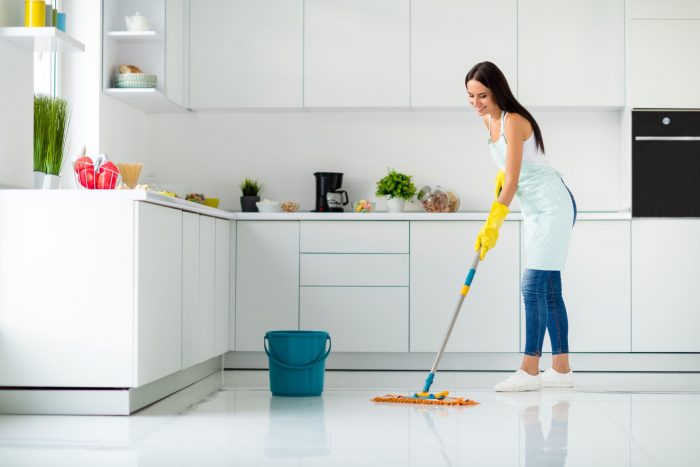 A cleaner mopping a bright kitchen