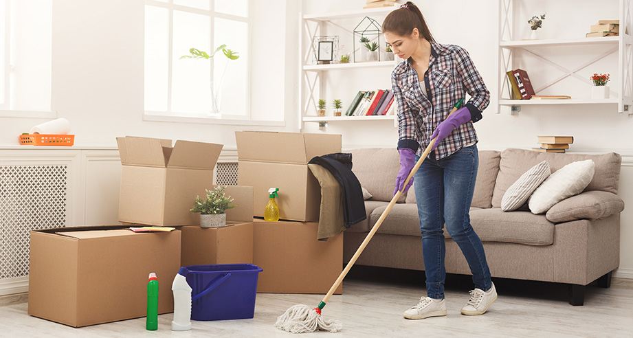 A cleaner mopping a home with moving boxes ready for a new resident